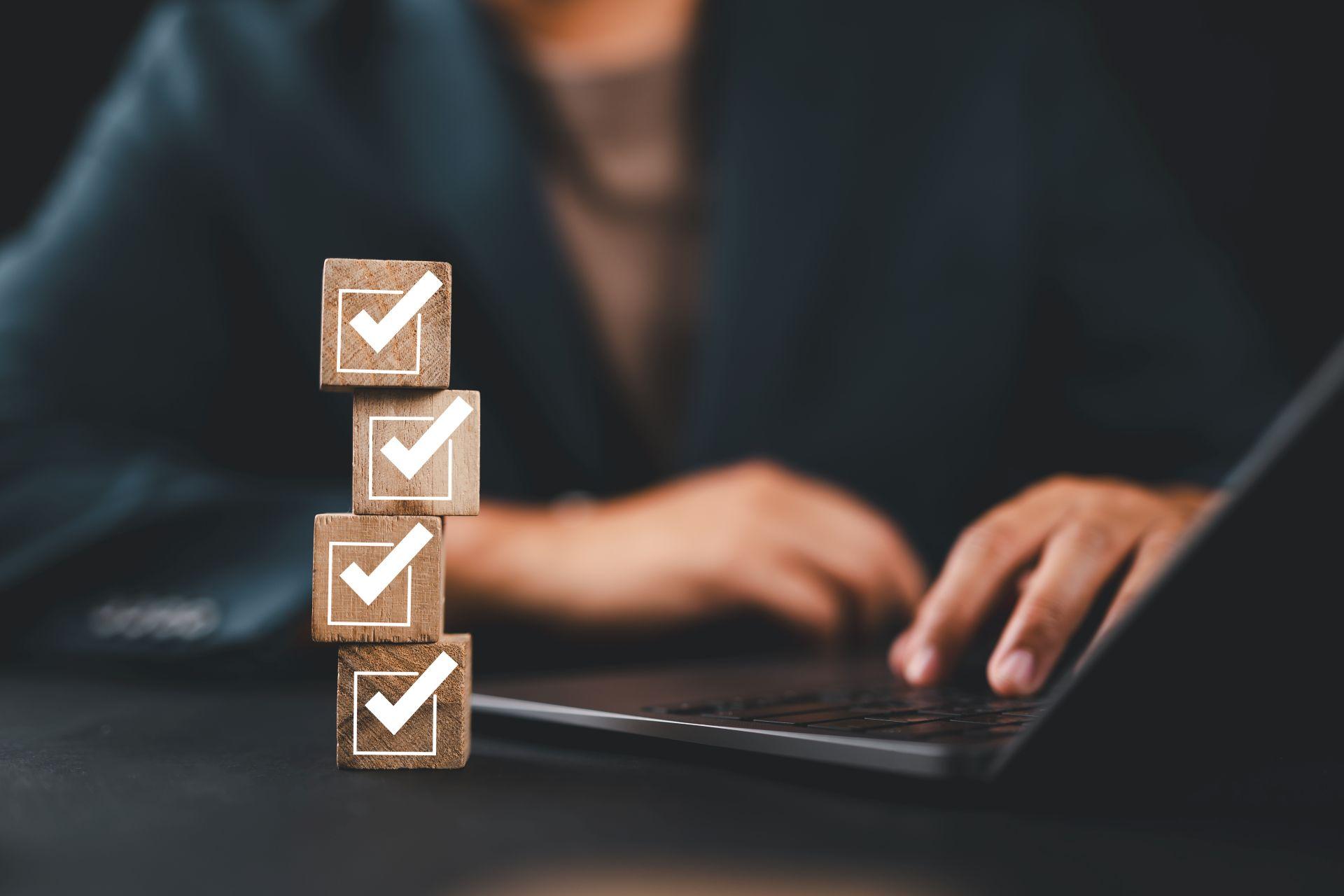 Checklist blocks on desk with professional using laptop – representing essential steps to consider when choosing structured help like an onlyfans agency